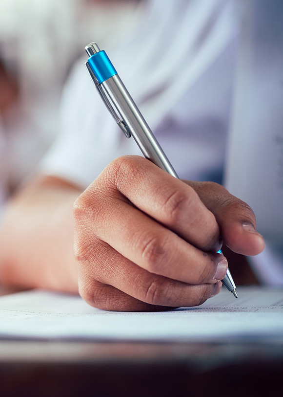 close up of students hand holding pen writing on paper