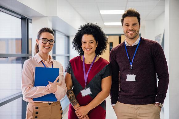 smiling staff, teacher concept, standing in empty school hallway